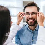 man being fitted for glasses by eye doctor